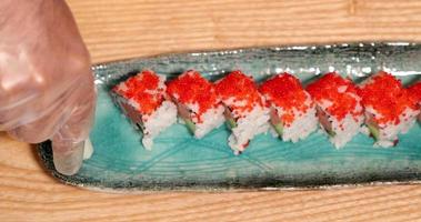 A Chef Squeeze And Puts Wasabi Paste On The Side Of A Sushi Rolls. - high angle  - slow motion video