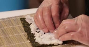 mettendo e organizzazione riso per un' delizioso kabuki Sushi rotolo - lento movimento video