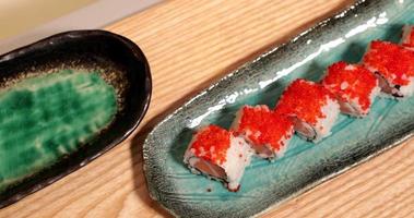 Delicious Sushi Rolls In A Plate Topped With Orange Roe Tobiko - high angle panning shot, slow motion video