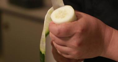 um chef segurando em uma mão o pepino e cortá-lo ao redor da circunferência fazendo folha de pepino para rolo de sushi. - tiro de perto video