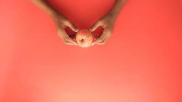 kind jongen hand- houden een appel Aan rood achtergrond video