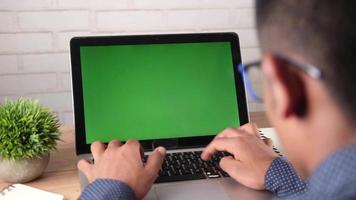 mans handen gebruik makend van laptop met groen scherm Aan tafel video