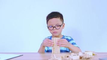 asiatischer junge, der mit einem holzpuzzle spielt video