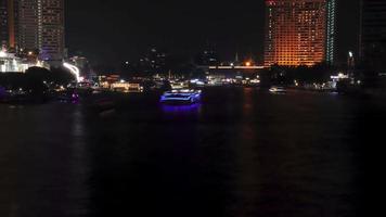 lapso de tiempo de hermosas luces de transporte público de agua, tráfico de barcos en el río chao phraya con edificios de condominios. hoteles de noche en bangkok, capital de tailandia video
