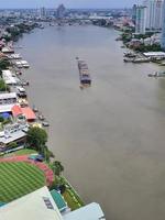 vista aérea de un pequeño remolcador remolcando una gran barcaza de arena, un bote de arena que lleva una carga de arena en el río chao phraya en bangkok, tailandia foto