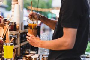 hombre barista haciendo café con leche saludable con bebida de cúrcuma en el mostrador bar café al aire libre. foto