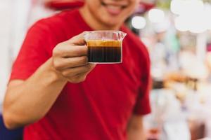 Barista holding a glass of espresso shot. photo