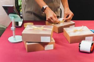 mujer propietaria de una pequeña empresa caja de embalaje en la entrega de la mesa al cliente. foto