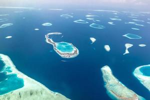 Aerial view of Maldives islands and atolls. Maldives tourism and travel background. Amazing blue sea, coral reef and atoll drone view. Beautiful nature landscape, seascape, exotic destination photo