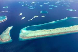 Aerial view of Maldives islands and atolls. Maldives tourism and travel background. Amazing blue sea, coral reef and atoll drone view. Beautiful nature landscape, seascape, exotic destination photo