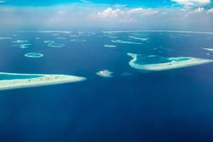 Aerial view of Maldives islands and atolls. Maldives tourism and travel background. Amazing blue sea, coral reef and atoll drone view. Beautiful nature landscape, seascape, exotic destination photo