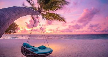 Tropical sunset beach as summer landscape with beach swing or hammock and white sand, colorful sky and sea shore. Beautiful beach banner vacation and summer holiday concept. Boost up color process photo