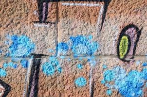 Fragment of graffiti drawings. The old wall decorated with paint stains in the style of street art culture. Colored background texture in warm tones photo