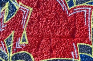 Fragment of graffiti drawings. The old wall decorated with paint stains in the style of street art culture. Colored background texture in warm tones photo