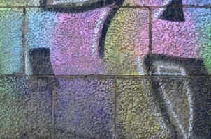 Fragment of graffiti drawings. The old wall decorated with paint stains in the style of street art culture. Multicolored background texture photo