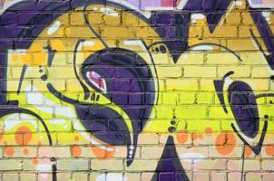 Fragment of graffiti drawings. The old wall decorated with paint stains in the style of street art culture. Colored background texture in warm tones photo