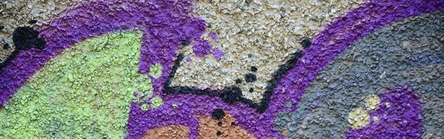 Fragment of graffiti drawings. The old wall decorated with paint stains in the style of street art culture. Colored background texture in warm tones photo