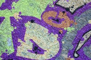 fragmento de dibujos de graffiti. la antigua muralla decorada con manchas de pintura al estilo de la cultura del arte callejero. textura de fondo coloreada en tonos cálidos foto