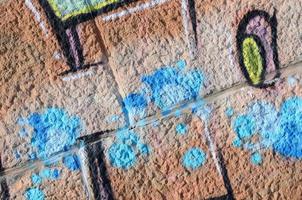 Fragment of graffiti drawings. The old wall decorated with paint stains in the style of street art culture. Colored background texture in warm tones photo