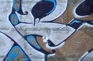Fragment of graffiti drawings. The old wall decorated with paint stains in the style of street art culture. Colored background texture in warm tones photo