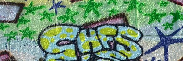 fragmento de dibujos de graffiti. la antigua muralla decorada con manchas de pintura al estilo de la cultura del arte callejero. textura de fondo coloreada en tonos verdes foto