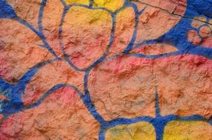 fragmento de dibujos de graffiti. la antigua muralla decorada con manchas de pintura al estilo de la cultura del arte callejero. flor naranja foto