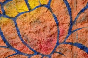 fragmento de dibujos de graffiti. la antigua muralla decorada con manchas de pintura al estilo de la cultura del arte callejero. flor naranja foto