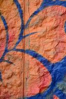 Fragment of graffiti drawings. The old wall decorated with paint stains in the style of street art culture. Orange flower photo