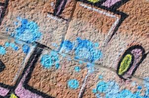 Fragment of graffiti drawings. The old wall decorated with paint stains in the style of street art culture. Colored background texture in warm tones photo