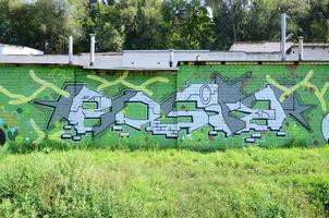 fragmento de dibujos de graffiti. la antigua muralla decorada con manchas de pintura al estilo de la cultura del arte callejero. textura de fondo coloreada en tonos verdes foto