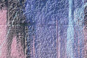 Fragment of graffiti drawings. The old wall decorated with paint stains in the style of street art culture. Colored background texture in purple tones photo