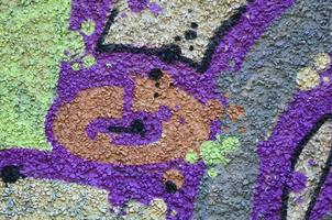 Fragment of graffiti drawings. The old wall decorated with paint stains in the style of street art culture. Colored background texture in warm tones photo