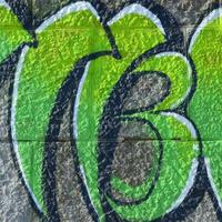 fragmento de dibujos de graffiti. la antigua muralla decorada con manchas de pintura al estilo de la cultura del arte callejero. textura de fondo coloreada en tonos verdes foto