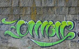 Fragment of graffiti drawings. The old wall decorated with paint stains in the style of street art culture. Colored background texture in green tones photo