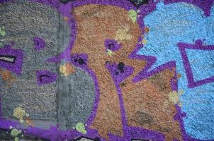 Fragment of graffiti drawings. The old wall decorated with paint stains in the style of street art culture. Colored background texture in warm tones photo