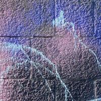 Fragment of graffiti drawings. The old wall decorated with paint stains in the style of street art culture. Colored background texture in purple tones photo