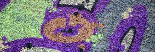 Fragment of graffiti drawings. The old wall decorated with paint stains in the style of street art culture. Colored background texture in warm tones photo