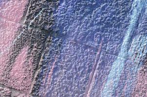 Fragment of graffiti drawings. The old wall decorated with paint stains in the style of street art culture. Colored background texture in purple tones photo