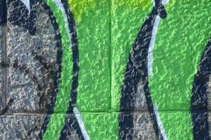 Fragment of graffiti drawings. The old wall decorated with paint stains in the style of street art culture. Colored background texture in green tones photo