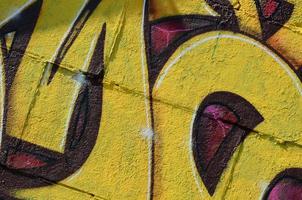 fragmento de dibujos de graffiti. la antigua muralla decorada con manchas de pintura al estilo de la cultura del arte callejero. textura de fondo coloreada en tonos cálidos foto