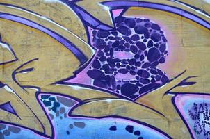 Fragment of graffiti drawings. The old wall decorated with paint stains in the style of street art culture. Colored background texture in purple tones photo