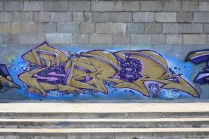 Fragment of graffiti drawings. The old wall decorated with paint stains in the style of street art culture. Colored background texture in purple tones photo