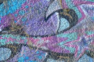 Fragment of graffiti drawings. The old wall decorated with paint stains in the style of street art culture. Colored background texture in purple tones photo