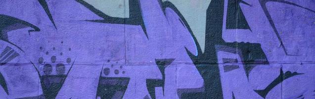 Fragment of graffiti drawings. The old wall decorated with paint stains in the style of street art culture. Colored background texture in purple tones photo