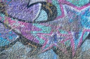 Fragment of graffiti drawings. The old wall decorated with paint stains in the style of street art culture. Colored background texture in purple tones photo