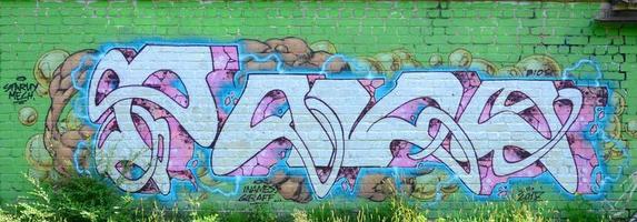 Fragment of graffiti drawings. The old wall decorated with paint stains in the style of street art culture. Colored background texture in green tones photo