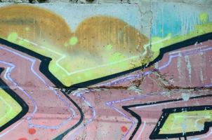 Fragment of graffiti drawings. The old wall decorated with paint stains in the style of street art culture. Colored background texture in warm tones photo