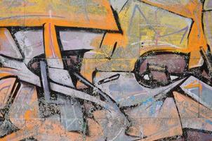 Fragment of graffiti drawings. The old wall decorated with paint stains in the style of street art culture. Colored background texture in warm tones photo