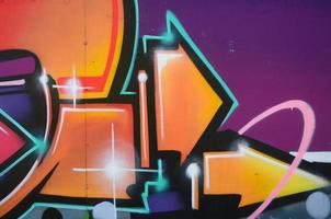 Fragment of graffiti drawings. The old wall decorated with paint stains in the style of street art culture. Colored background texture in warm tones photo