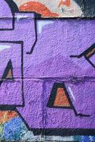 Fragment of graffiti drawings. The old wall decorated with paint stains in the style of street art culture. Colored background texture in purple tones photo